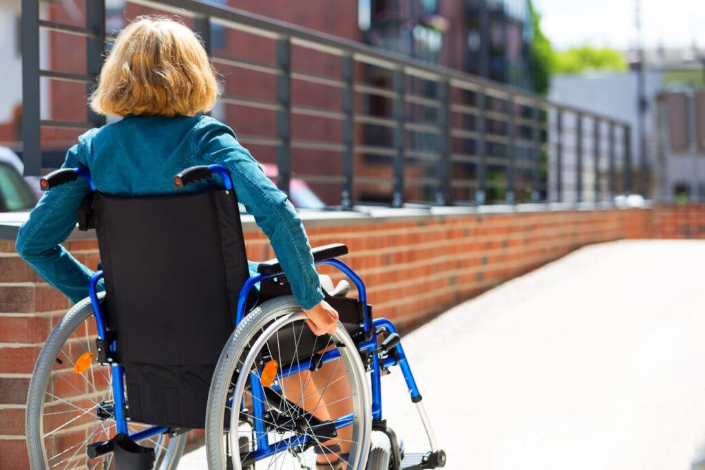 Woman uses a wheelchair on a ramp outside of a business.